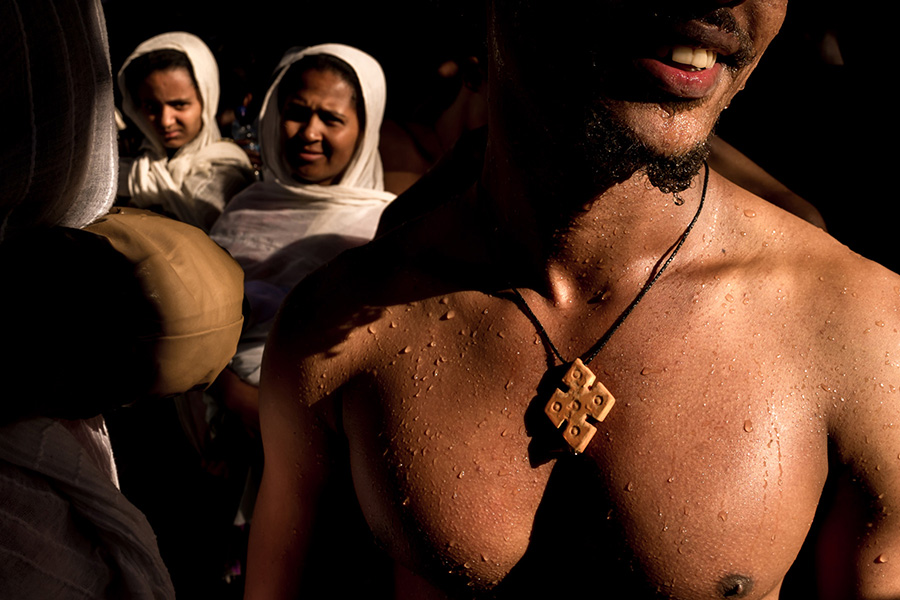 A young man is warming up in the sun after entering the cold holy water of Gondar, Ethiopia.